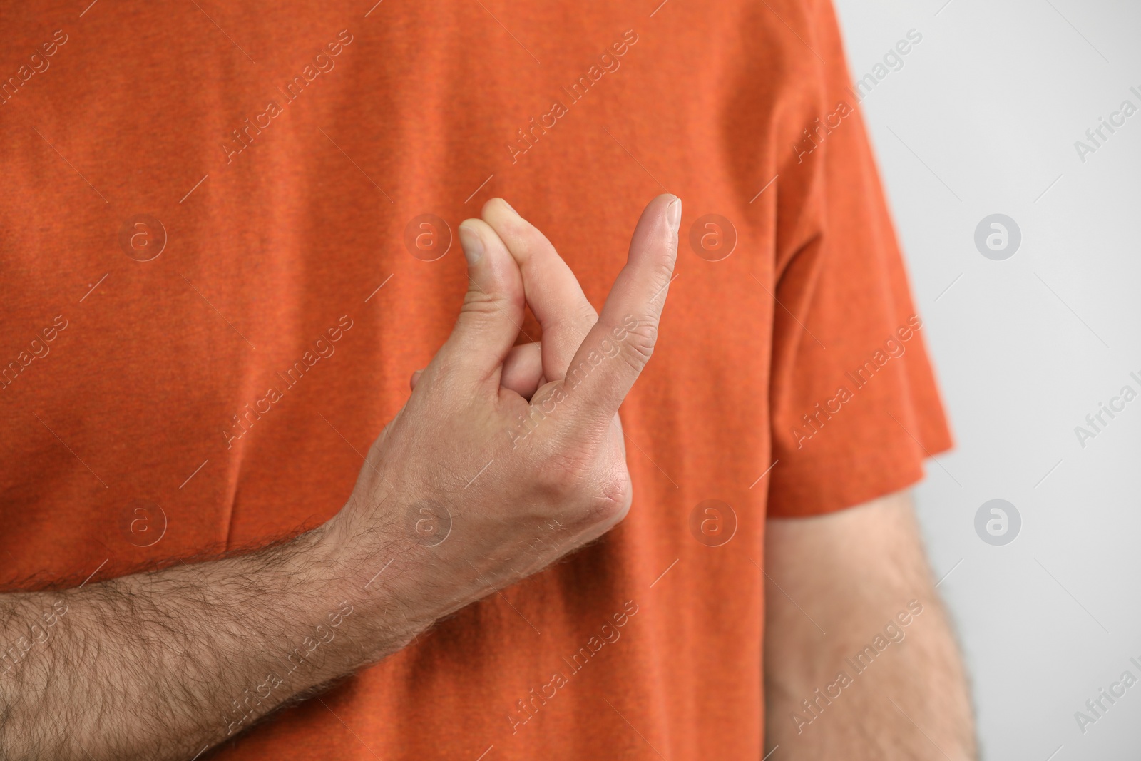 Photo of Man snapping his fingers on light grey background, closeup. Bad habit