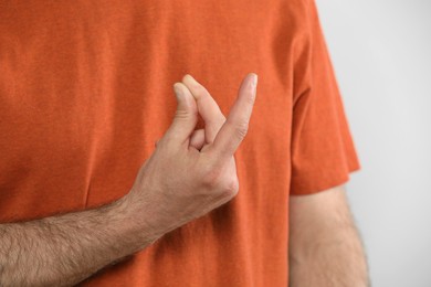 Photo of Man snapping his fingers on light grey background, closeup. Bad habit