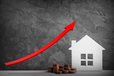 Mortgage concept. House model and coins on white table against grey background 