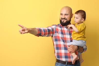 Portrait of dad and his little son on color background