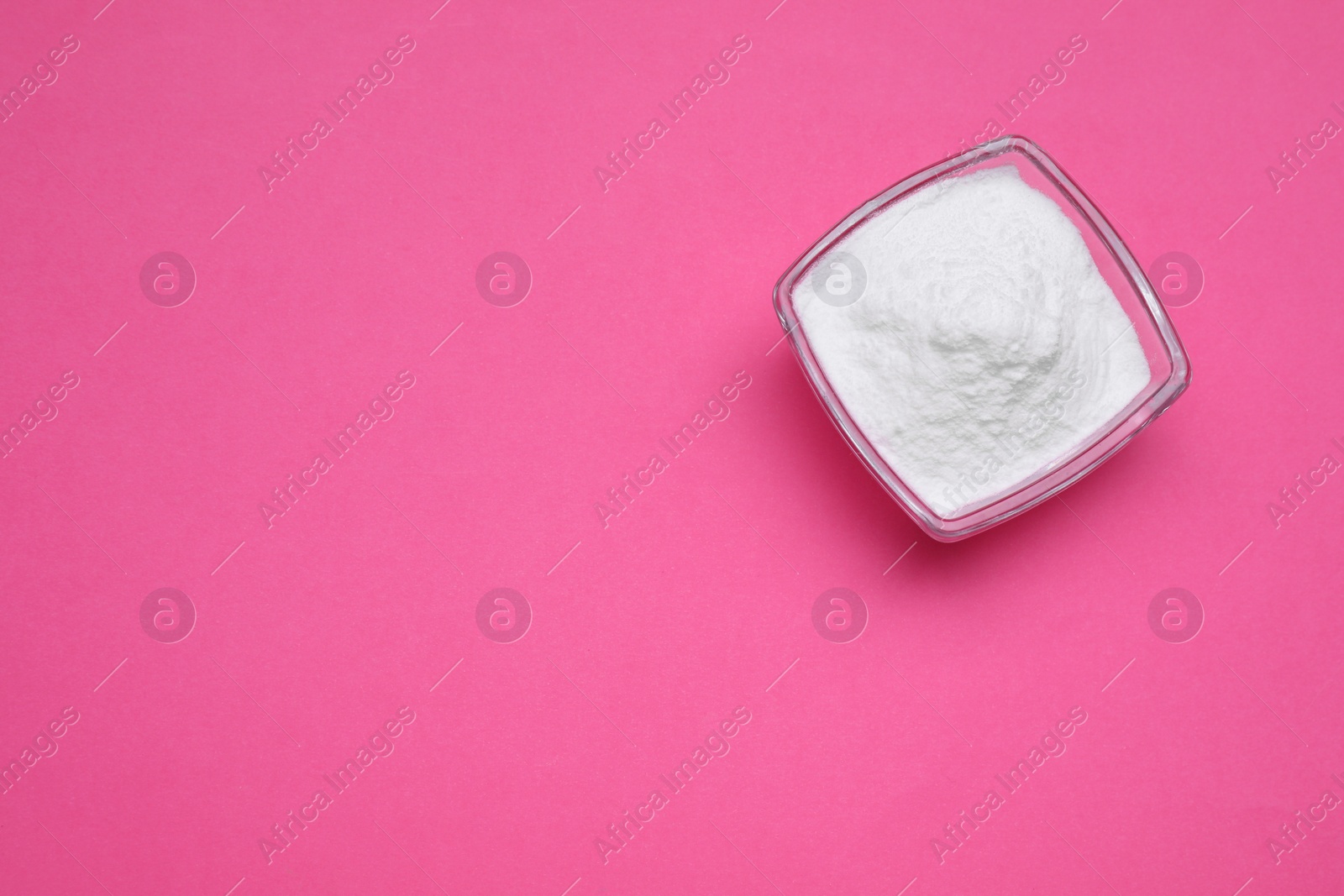 Photo of Bowl of sweet powdered fructose on pink background, top view. Space for text