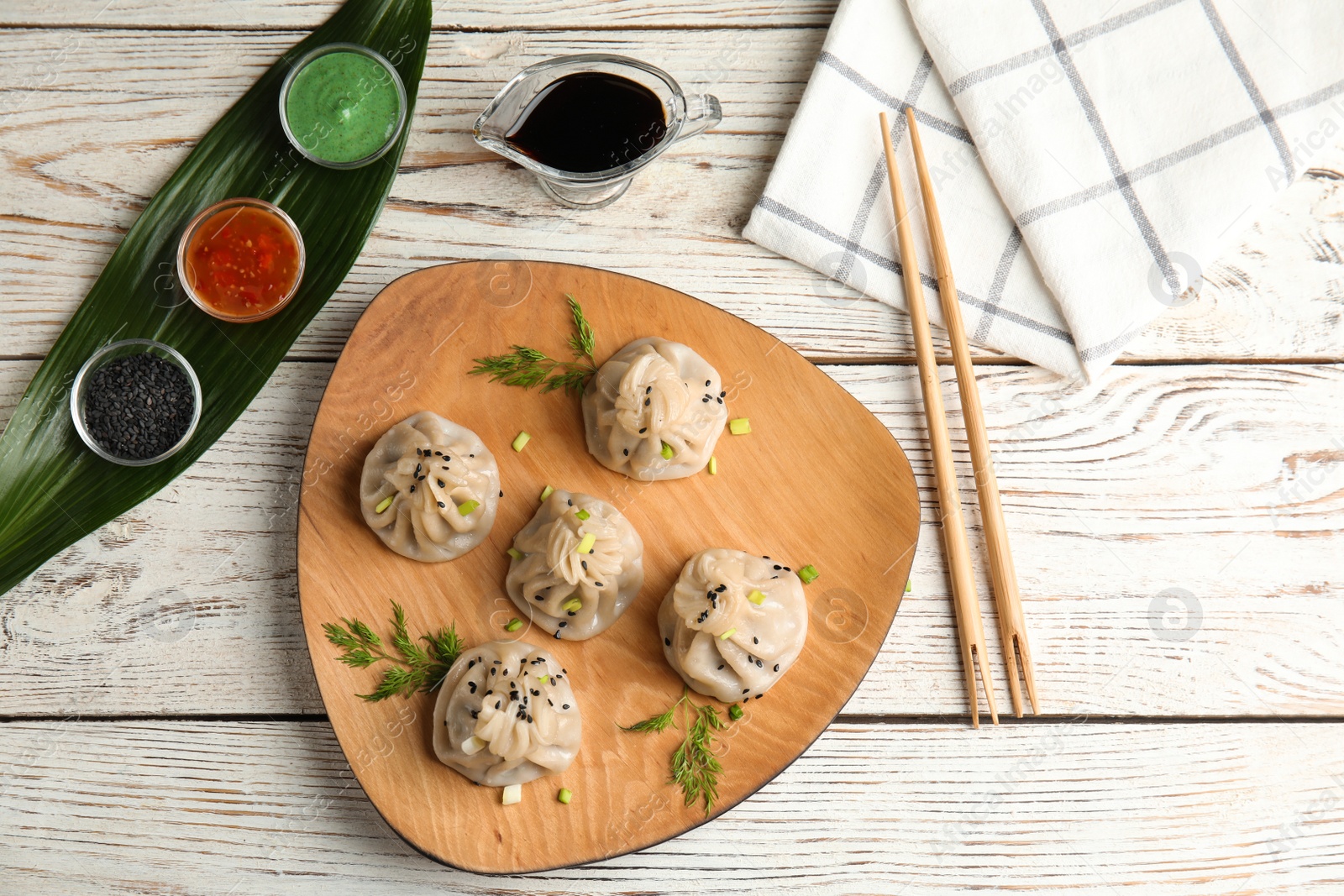 Photo of Flat lay composition with plate of tasty baozi dumplings and sauces on white wooden table