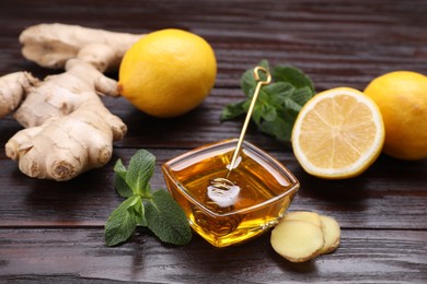 Photo of Natural cough remedies. Bowl with honey, ginger, lemon and mint on wooden table