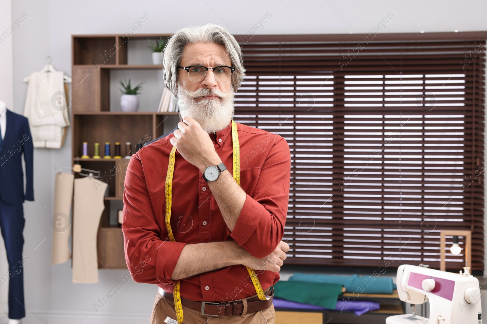 Photo of Professional tailor with measuring tape in workshop