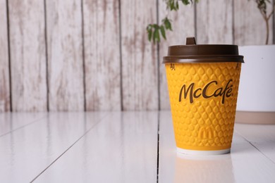 Photo of MYKOLAIV, UKRAINE - AUGUST 12, 2021: Hot McDonald's drink on white wooden table. Space for text