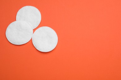 Clean cotton pads on orange background, flat lay. Space for text