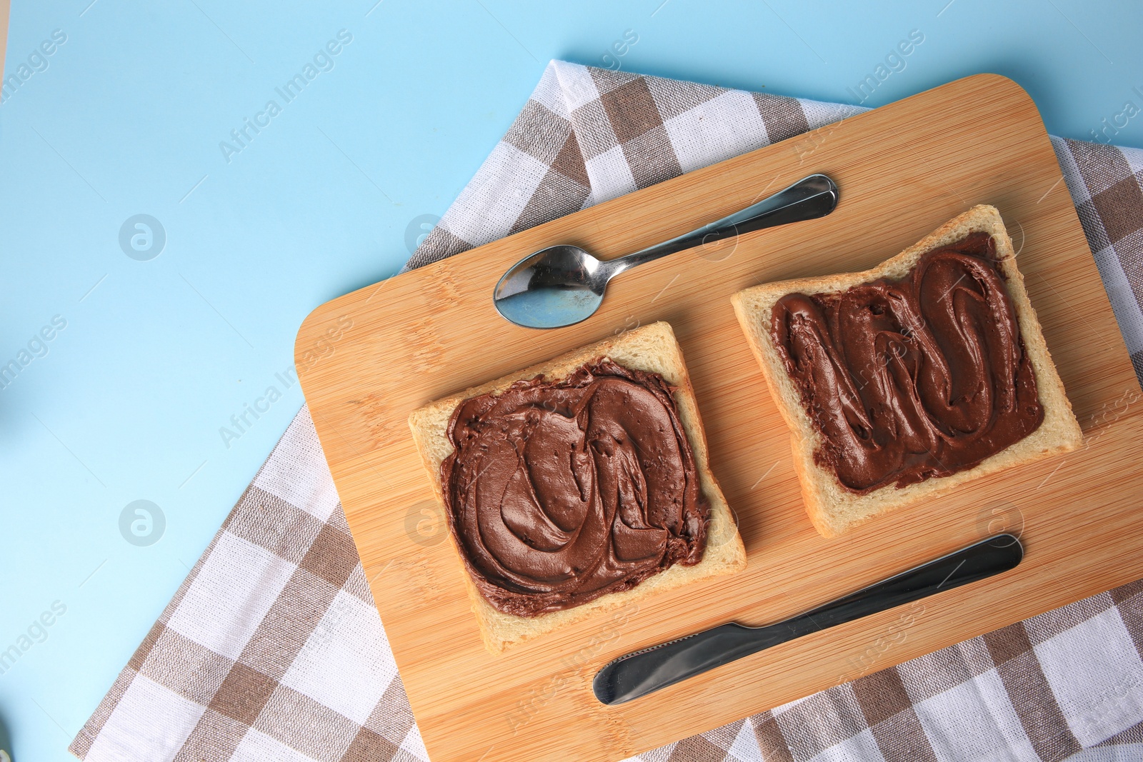 Photo of Tasty toasts with chocolate paste served on light blue background, top view. Space for text