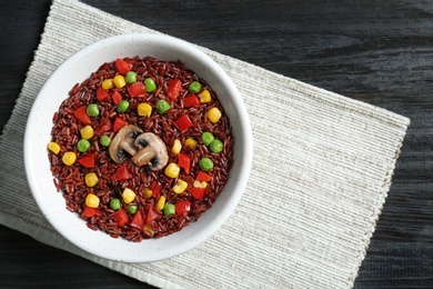 Bowl with cooked brown rice served on table, top view. Space for text