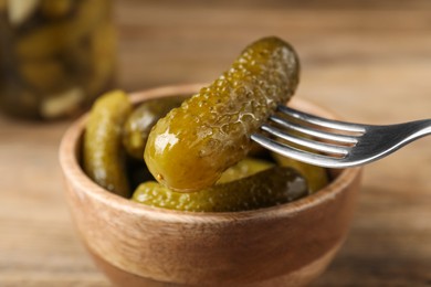 Eating tasty pickled cucumber at table, closeup