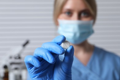 Photo of Doctor holding pill on light background, selective focus