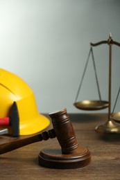 Photo of Construction and land law concepts. Gavel, scales of justice, hard hat and hammer on wooden table