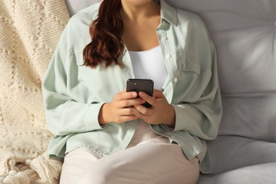 Photo of Young woman with smartphone sitting on sofa, closeup