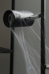 Cobweb on lamp against gray background, closeup