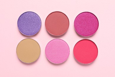 Different beautiful eye shadows on pink background, flat lay