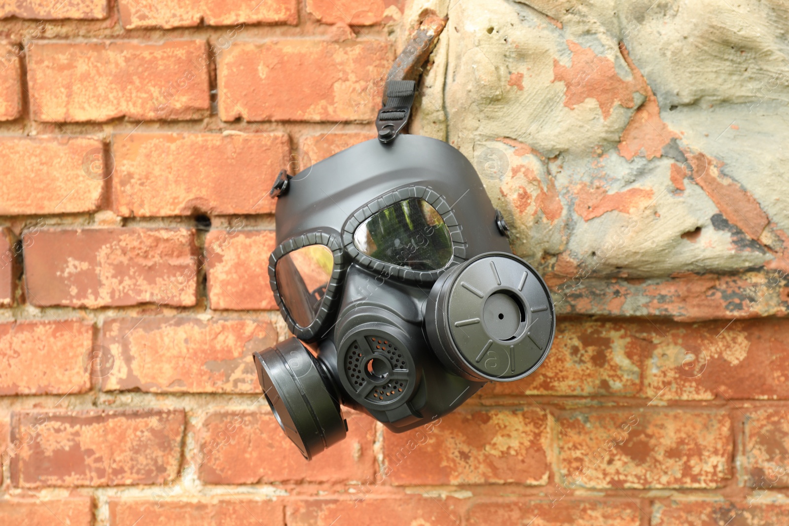 Photo of One gas mask hanging near brick wall on building