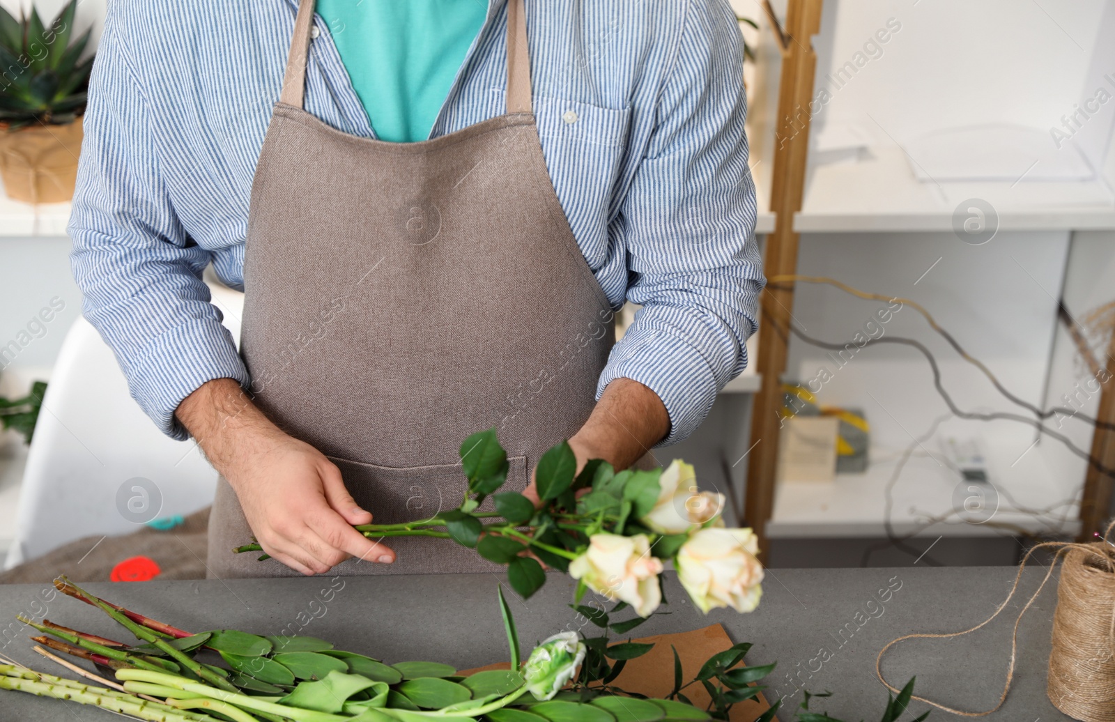 Photo of Florist making bouquet with fresh flowers at table, closeup