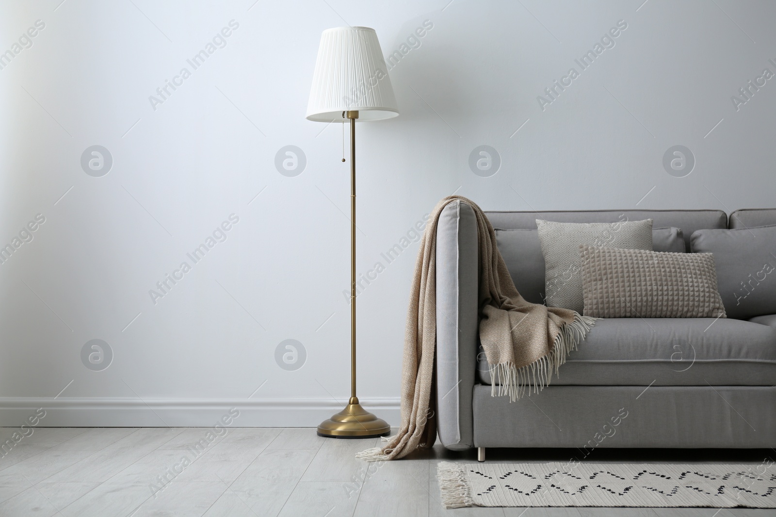 Photo of Grey sofa with pillows near white wall in stylish living room interior
