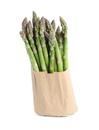 Photo of Fresh raw asparagus in paper bag isolated on white. Healthy eating