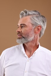 Photo of Portrait of confident man with beautiful hairstyle on light brown background