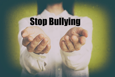 Young woman showing sign STOP BULLYING on yellow background, closeup