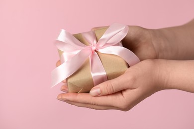 Photo of Woman holding gift box with bow on pink background, closeup