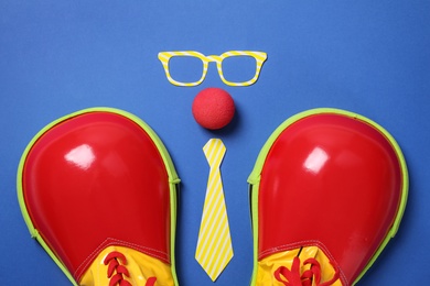Photo of Flat lay composition with shoes, paper glasses, nose and tie on blue background