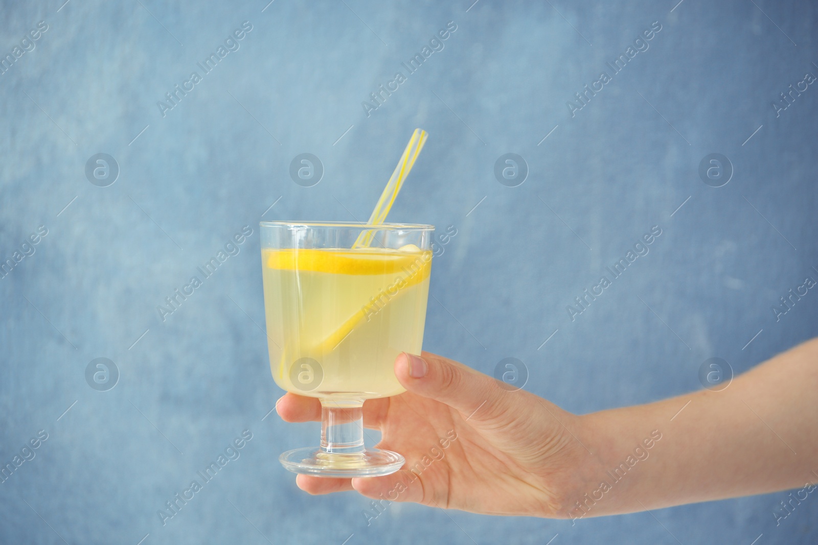 Photo of Young woman holding glass with lemon cocktail against color background