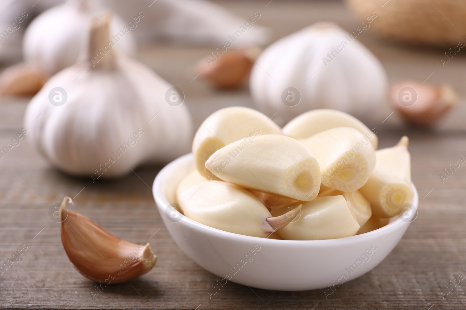 Photo of Aromatic garlic cloves and bulbs on wooden table, closeup. Space for text