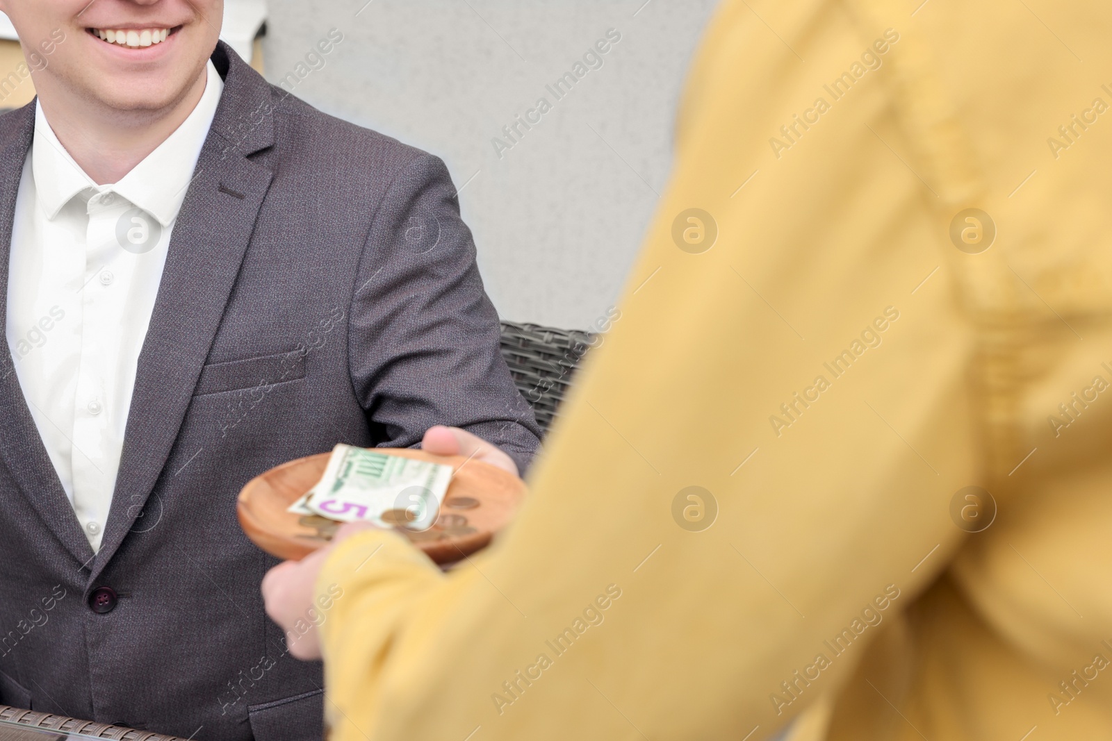 Photo of Happy client giving tips to waitress in outdoor cafe, closeup