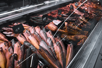 Photo of Showcase with different smoked fish in supermarket