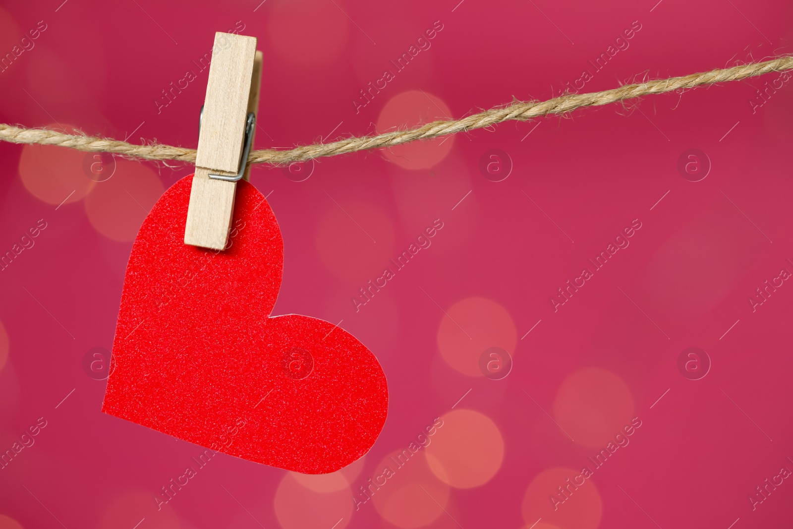 Photo of Decorative heart hanging on twine against pink background, space for text. Valentine's Day