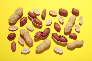Fresh peanuts on yellow background, flat lay