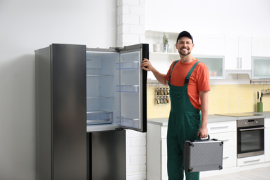 Male technician with tool box near refrigerator indoors