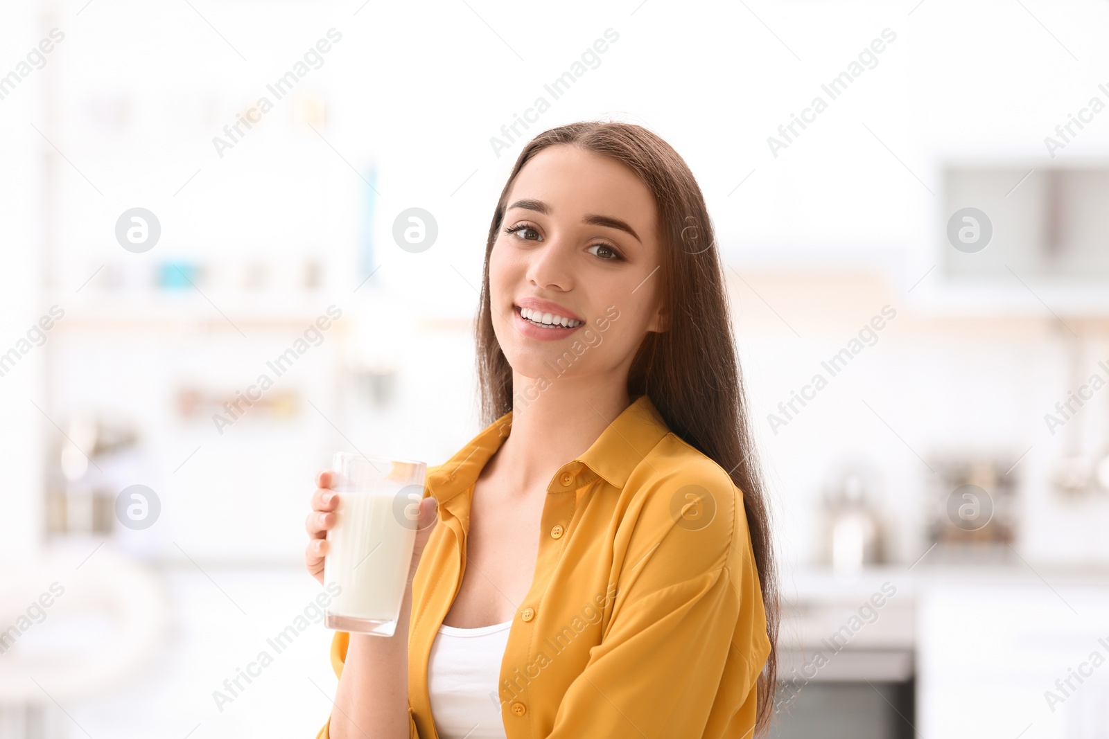 Photo of Beautiful young woman drinking milk at home