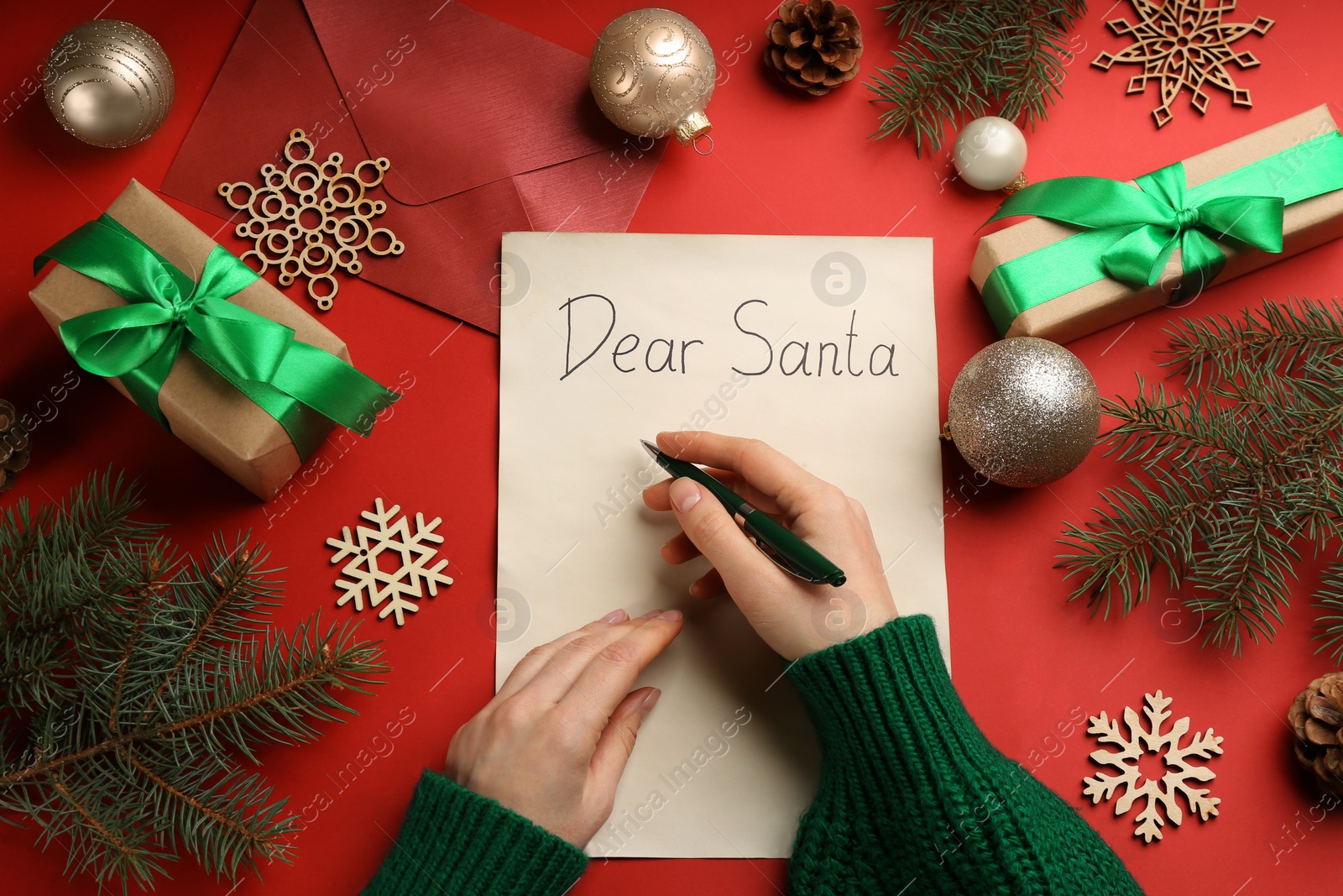 Photo of Top view of woman writing letter to Santa at red table, closeup