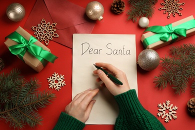 Photo of Top view of woman writing letter to Santa at red table, closeup