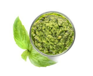 Photo of Bowl of tasty pesto sauce with basil leaves isolated on white, top view