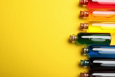 Photo of Bottles with different food coloring on yellow background, flat lay. Space for text