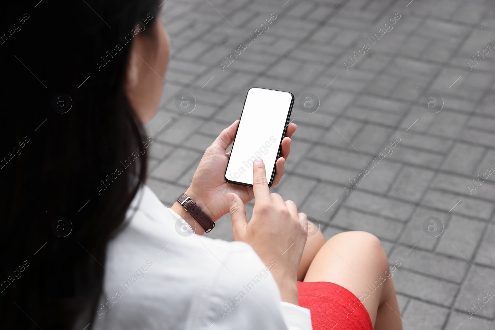 Photo of Closeup of woman with smartphone sitting on bench outdoors