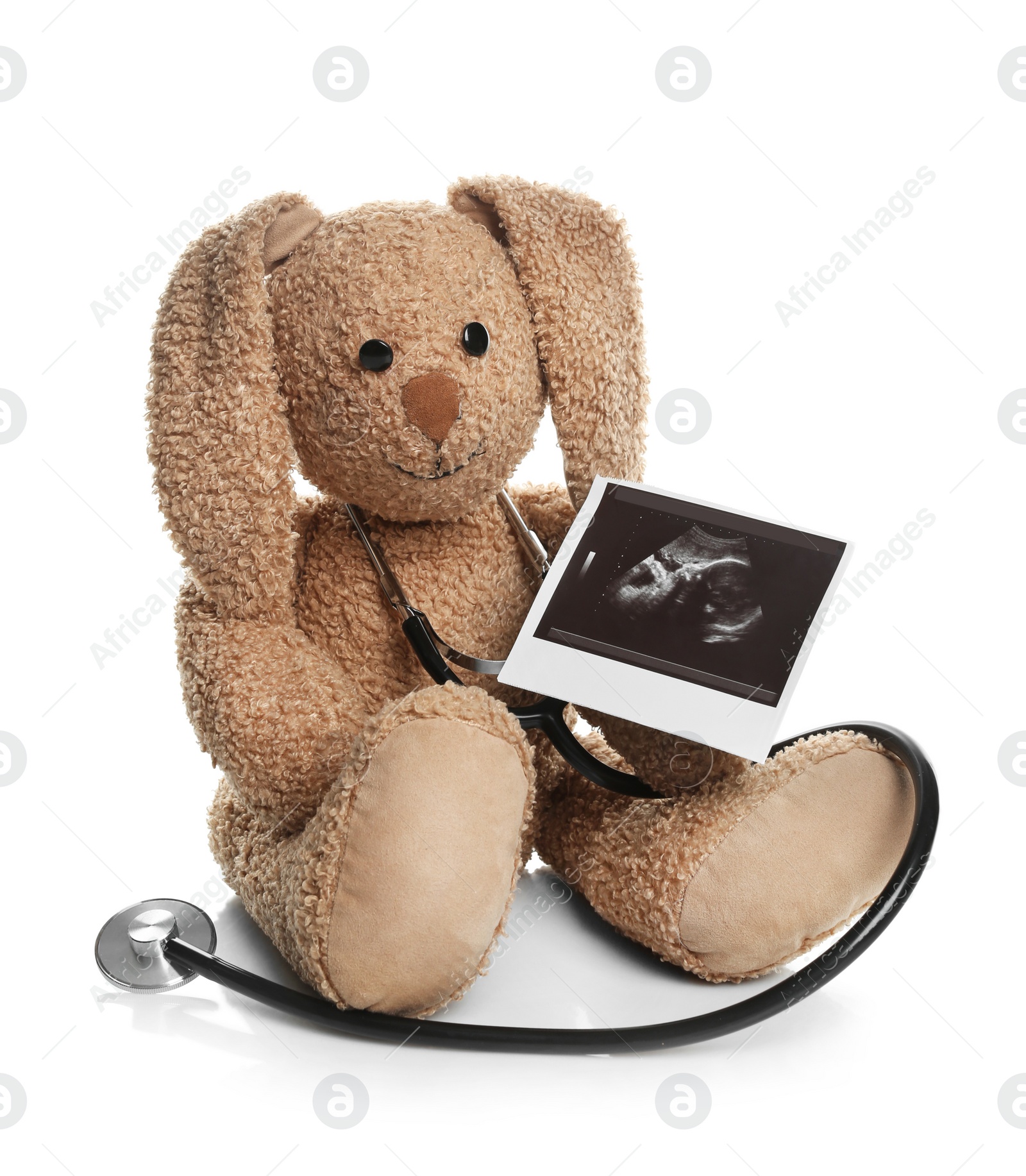 Photo of Ultrasound photo of baby and toy rabbit on white background. Concept of pregnancy