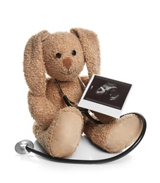 Ultrasound photo of baby and toy rabbit on white background. Concept of pregnancy