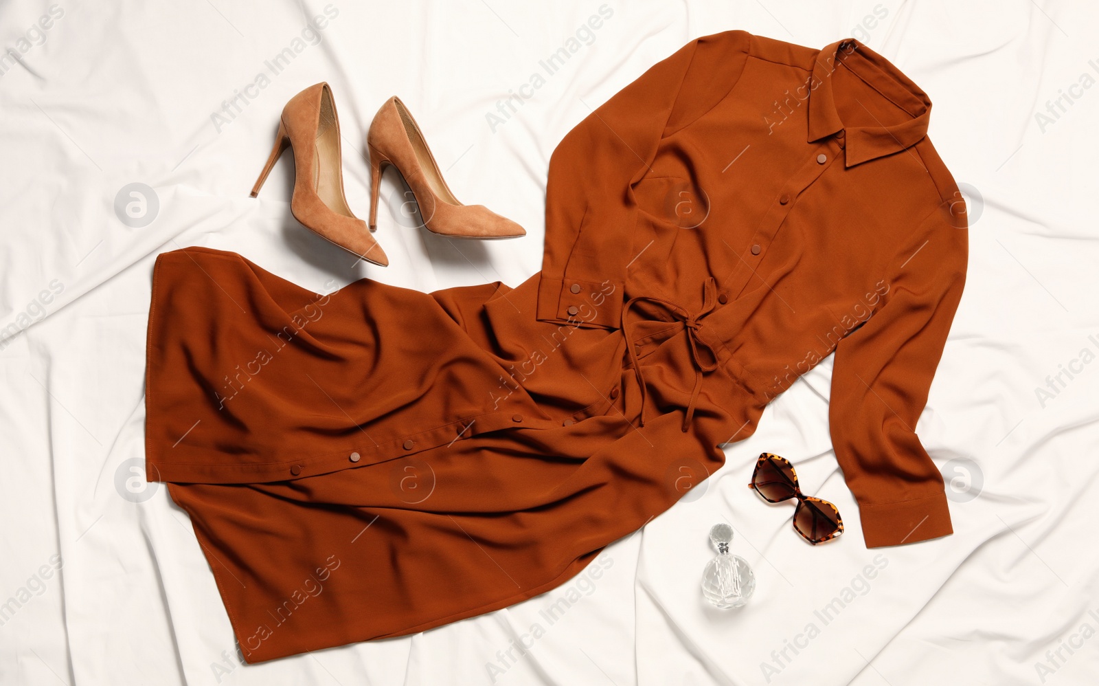 Photo of Flat lay composition with stylish dress on white fabric