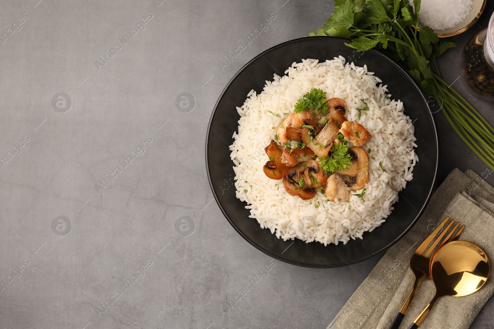 Photo of Delicious rice with parsley and mushrooms served on grey table, flat lay. Space for text
