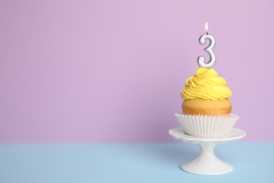 Photo of Birthday cupcake with number three candle on stand against color background, space for text