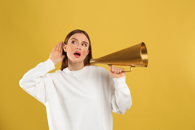 Photo of Emotional young woman with vintage megaphone on yellow background