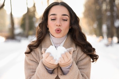 Photo of Portrait of beautiful woman blowing snow from hands in park