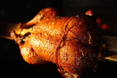Photo of Grilling whole delicious duck in rotisserie machine, closeup