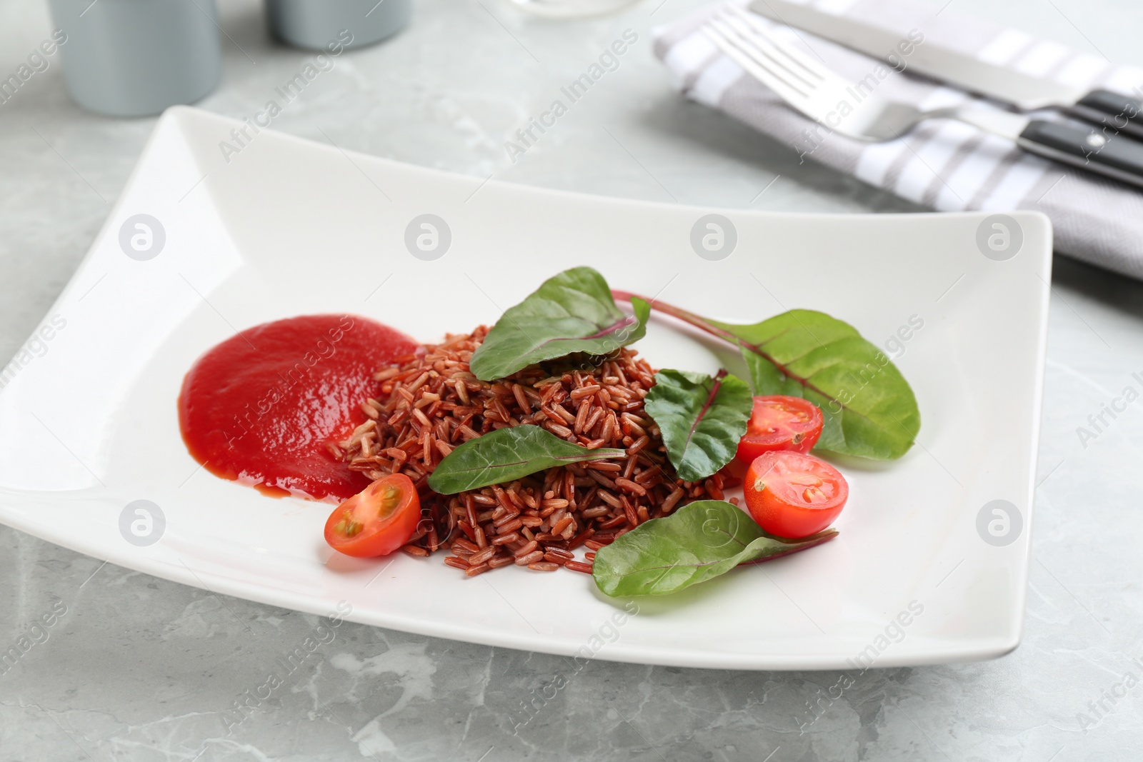 Photo of Tasty brown rice served on light grey table