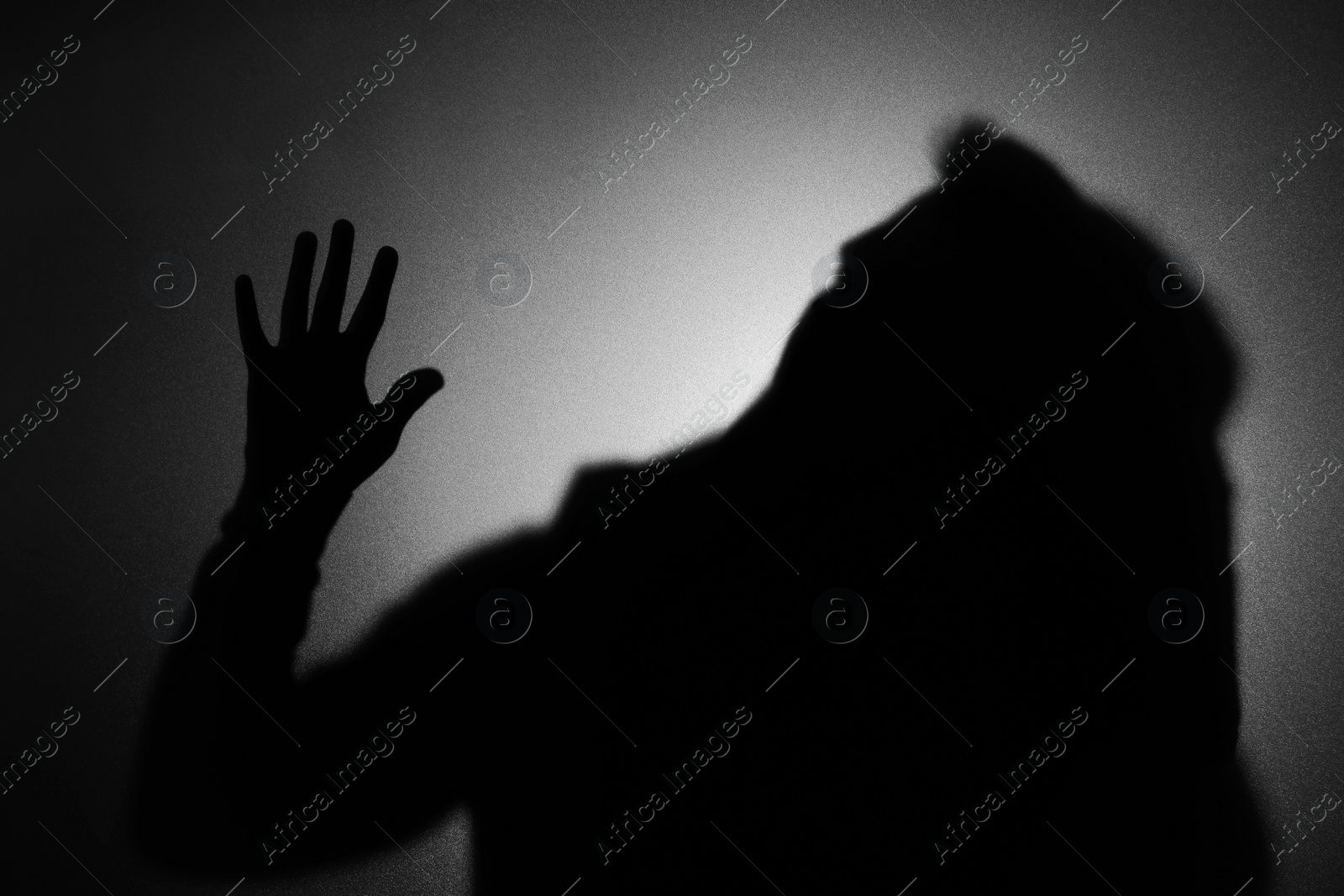 Photo of Silhouette of ghost behind glass against dark background