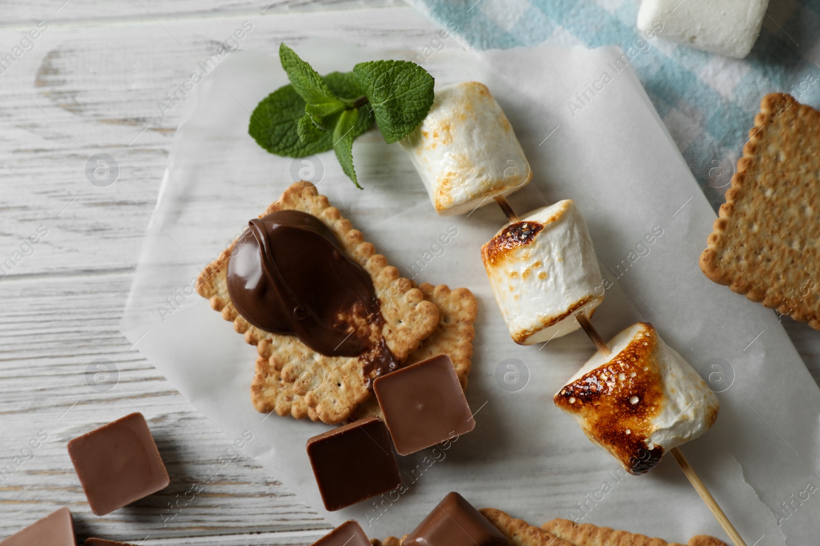 Photo of Ingredients for delicious sandwich with roasted marshmallows and chocolate on white wooden table, flat lay